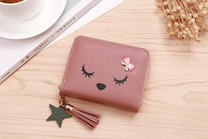 Close-up of pink tassel, star pendant, and heart bow on a cute cartoon zipped wallet