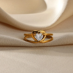 Macro shot of double-layer gold ring with heart-shaped zircon on beige silk fabric