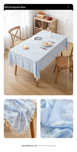 Close-up of light blue floral cotton linen tablecloth with cream tassel edge detail