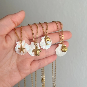Close-up of 18K gold plated starfish and seashell pendants on ocean-themed necklaces