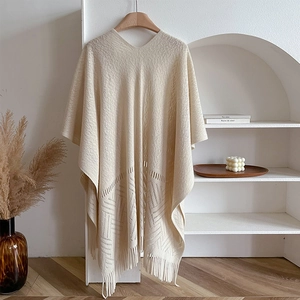 Beige hollow-out knit shawl with tassel hem displayed on a minimalist wooden wall shelf