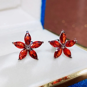 Macro shot of red five-petal flower stud earrings with marquise-cut stones in a jewelry box