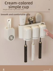 Detail of wall-mounted cream toothbrush holder with three magnetic cups and toothpaste dispenser
