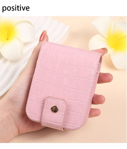 Detailed macro view of pink crocodile leather lipstick case with mirror and gold buckle