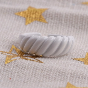 Detailed view of white enamel croissant ring with spiral texture on star pattern cloth