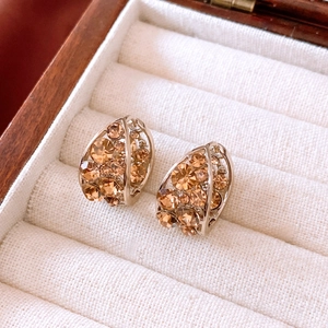 Dettaglio di orecchini vintage a forma di U con strass champagne in confezione regalo