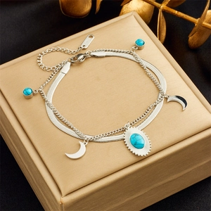Detail of silver double-layer stainless steel bracelet with moon and turquoise pendants