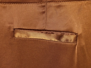 Close-up of the satin brown wide-leg trousers showing a welt pocket and detailed stitching