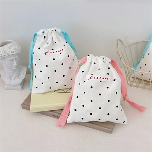 Detail of polka dot canvas drawstring bags featuring colorful cotton ropes and woven label