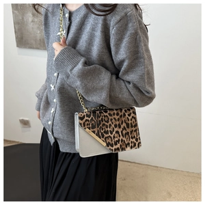 Detail of leopard print and grey panel crossbody bag with gold chain strap on model