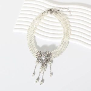 Close-up of triple-layer pearl necklace with rhinestone heart pendant and tassels