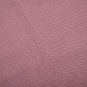 Detail shot of dusty pink corduroy fabric showing vertical ribs and flat seam stitching