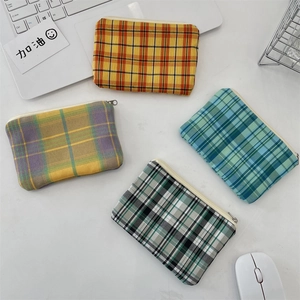 Vue à plat de petites pochettes à carreaux zippées en quatre couleurs sur un bureau