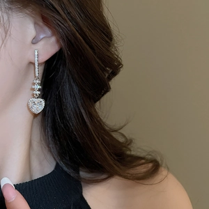 Close-up of model wearing silver heart-shaped zircon drop earrings with elegant vertical design