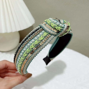 Detail of hand-woven green and bronze headband with sequins and faux pearls