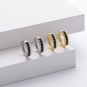 Detailed macro view of gold and silver spike hoop earrings with black zircon pavé