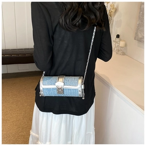 Blue denim barrel bag with silver leather trim and chain strap shown on a model