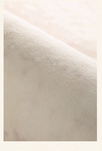 Vista macro de tela de terciopelo crema que muestra texturas finas y pliegues suaves