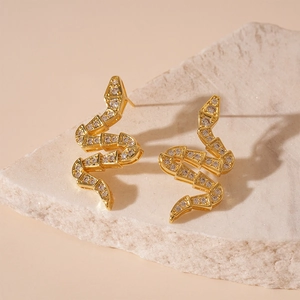 Detail shot of golden snake stud earrings with white zircon on minimalist stone