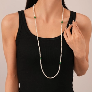 Détail d'un long collier de perles avec perles d'agate verte sur gilet noir