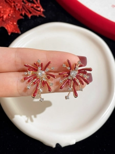 Macro shot of gold firework stud earrings with red glaze and heart-shaped zircon