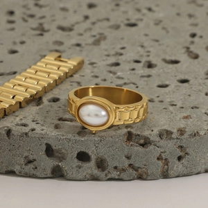 Vintage Goldring mit Perle und Kettenmuster auf Natursteinoberfläche präsentiert