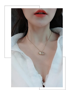 Detail of an asymmetric butterfly necklace with a white pearl on a gold chain