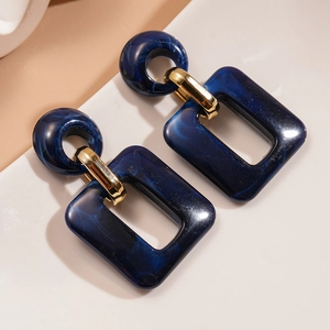 Detail of dark blue marble resin earrings with gold metal links on peach background