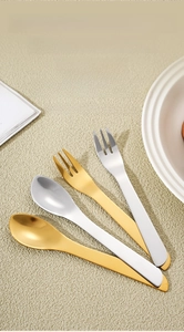 Macro shot of polished gold and silver stainless steel spoons and forks on textured background