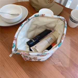 Quilted floral makeup bag with cute bear pattern and zipper on wooden desk detail