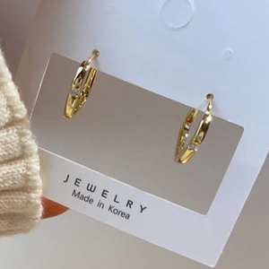 Detail shot of gold lattice earrings with fine diamond inlay held by a model