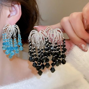 Detail of luxury tiered beaded tassel earrings in light blue and black crystal accents