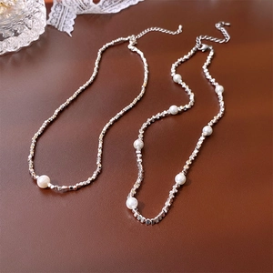 Vue détaillée du collier de perles argentées avec perles blanches sur un bureau vintage