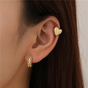 Close-up of gold heart ear cuff and sparkling zircon hoop earring set on model ear
