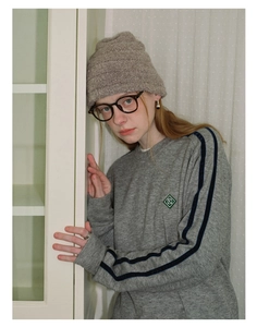 Detail of grey wool blend knit hat with rib texture worn by a model in a cozy indoor setting