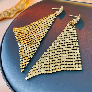 Macro shot of gold triangular mesh tassel earrings with sparkling rhinestone studs