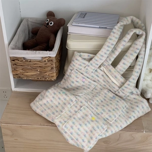 Detail of soft plush tote bag featuring multi-color plaid patterns and functional pockets