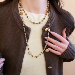 Close-up of bohemian double-layer beaded long necklace with gold chains and earth-toned beads