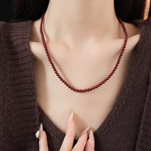 Detail of deep red beaded titanium steel necklace shown on a model's neck