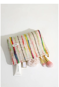 Détail de la trousse de maquillage tissée à rayures ethniques avec fermeture éclair dorée