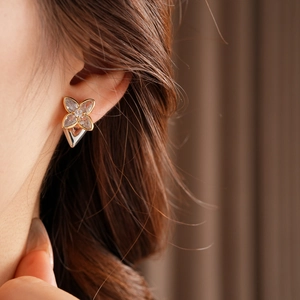 Detail view of a zircon four-leaf clover earring shown on a model for style and scale