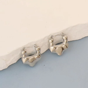Detailed view of silver oval hoop earrings with irregular textured polished metal surface
