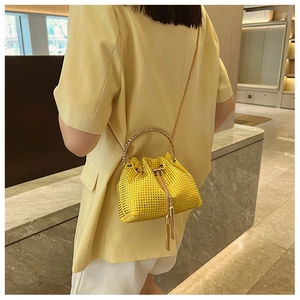 Detail of yellow rhinestone bucket bag with gold chain strap and tassel drawstring