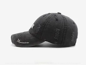 Close-up of distressed denim baseball cap with white cursive embroidery on the visor