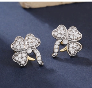 Macro shot of silver clover earrings with micro-pave crystals and gold stem details