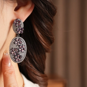 Detail of vintage flower earrings with purple gemstones and micro-pave crystals