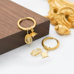 Detail view of gold hoop earrings with star charms and amazonite stones on silk cloth