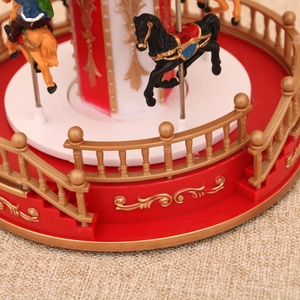 Detailed close-up of a red musical carousel base with golden accents and painted horses