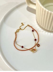 Detail of 18k gold plated double chain bracelet with red beads and a small horse pendant