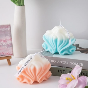 Artistic wavy scented candle with blue and orange gradients on a minimalist book set